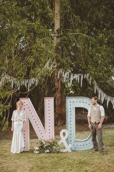 a man and woman standing in front of the letters n and d with flowers on them