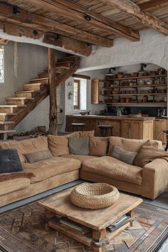 a living room filled with furniture and lots of wooden beams on the ceiling, next to a stair case