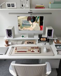 a desk with a computer, keyboard and speakers on it in front of a monitor