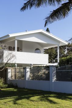 a white house sitting on top of a lush green field next to a tall palm tree