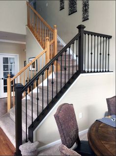 a dining room table and chairs under a stair case in a house with white walls