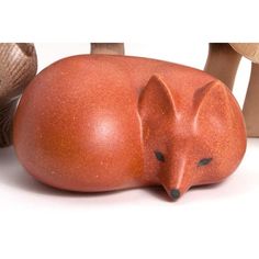 a ceramic fox laying on its side next to mushrooms