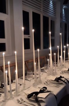 a long table is set with white candles and place settings for dinner guests to enjoy