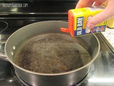 someone is cleaning the inside of a pan on the stove top with an orange spray bottle