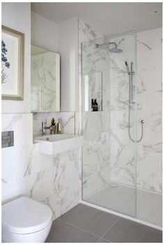 a white bathroom with marble walls and floor