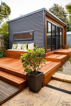 a small backyard with wooden steps leading up to the decking area and a potted plant