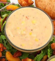 a salad with dressing in a bowl next to some bread and dipping sauce on the side