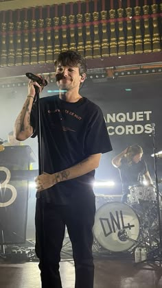 a man standing on top of a stage holding a microphone in his hand and singing