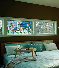 a bedroom with two stained glass windows and a tray on the bed in front of it