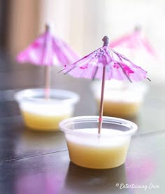 two small cups filled with liquid and an umbrella sticking out of the top, sitting on a table