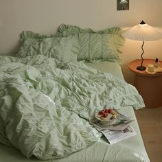 an unmade bed with a plate of fruit on it and a lamp next to it