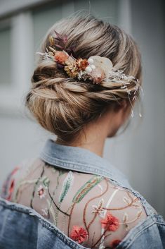 a woman with flowers in her hair is wearing a denim jacket and floral headpiece