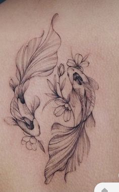 a woman's back with two goldfishs and flowers on the bottom side