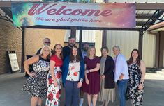 a group of people standing in front of a welcome sign