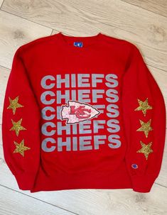 A vintage Champion Kansas City Chiefs graphic sweatshirt with a worn-in look and gold sparkly rhinestone stars down the sleeves. Heavy weight fabric. Small mark on back. Hand wash only Hang to dry Sizing: X-LargeMeasurements:Length: 26.5 inPit to pit width laying flat: 23 inSleeve length: 23 inShoulder to shoulder length: 20.5 in localE vintage pieces are pre-owned, one-of-a-kind pieces that are hand picked by us and reworked. This means that some may have small marks and a worn-in look. Any mar Long Sleeve Cotton Sweatshirt With Glitter Print, Cotton Glitter Print Long Sleeve Sweatshirt, Chicago Bulls Sweatshirt, University Of Kansas, Kc Chiefs, Vintage Type, Vintage Champion, Kansas City Chiefs, Vintage Pieces