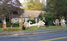 a group of people dressed up in costumes standing on the side of a road next to a house