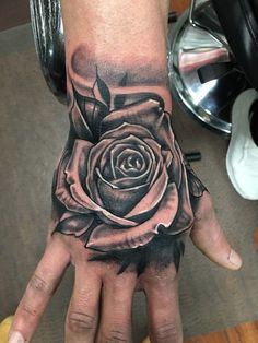 a hand with a black rose tattoo on it