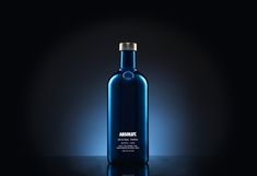 an empty blue bottle sitting on top of a black table next to a dark background