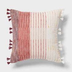 a red and white striped pillow with tassels