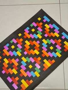 a piece of art that is made out of colored squares on the floor with black paper