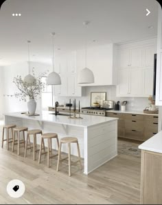 a large kitchen with white cabinets and counter tops, an island in the middle is surrounded by stools