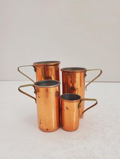 four old fashioned copper mugs sitting next to each other on a white counter top