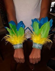 two hands with green and blue feathers on them