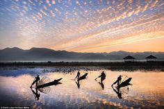 four people on small boats in the water with mountains in the backgrouds