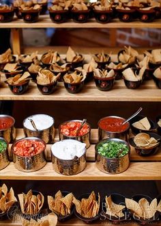 several trays filled with different types of food on wooden shelves next to each other