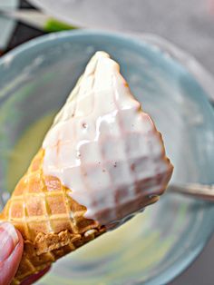 a person is holding a waffle with icing on it in a blue bowl