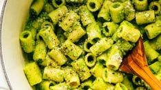 a wooden spoon in a pot filled with pasta and broccoli pesto sauce