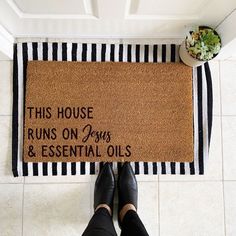 a door mat that says this house runs on dogs and essential oils next to a potted plant