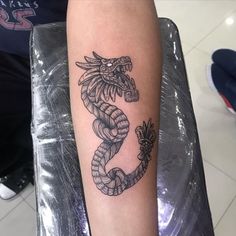 a black and white photo of a dragon tattoo on the arm, with its tail curled up