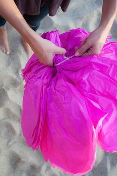 a person is holding a pink bag on the beach