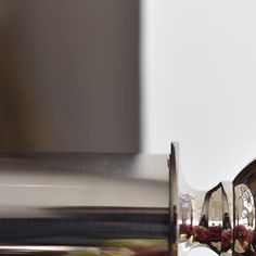 a close up of a silver cup with flowers on the side and a mirror behind it