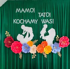 the backdrop is decorated with paper flowers and silhouettes of two women, one holding a baby