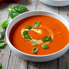 two bowls of tomato soup with basil garnish