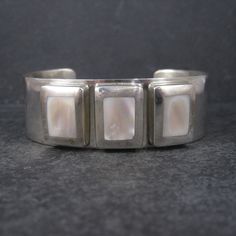 This gorgeous mother of pearl cuff bracelet is solid sterling silver. This bracelet measures 7/8ths of an inch wide. The inner dimensions measure 7 inches including a 1 1/2 inch gap. It weighs 54.3 grams. It is unmarked and unsigned. It does test as sterling silver. It is in phenomenal condition. White Sterling Silver Oyster Bangle Bracelet, White Bangle With Polished Finish As Gift, White Polished Cuff Jewelry, Pearl Cuff Bracelet, Pearl Cuff, Cuff Bracelet, Mother Of Pearl, Favorite Jewelry, Cuff Bracelets