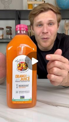 a man pointing at an orange juice bottle