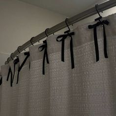 black and white shower curtain with ribbons hanging from it's side in a bathroom