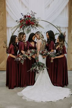 a group of women standing next to each other in front of a white wall with flowers