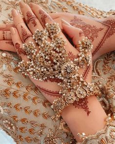 a woman's hands with henna and bracelets on her arm, both covered in pearls