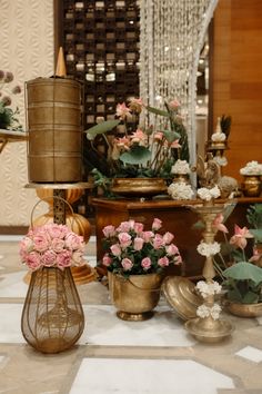 several vases filled with flowers sitting on top of a white and gold table cloth