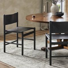 a dining room table with two chairs and a vase on the floor next to it