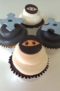 four cupcakes with frosting decorated as ninja and snowman faces on them