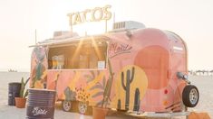 a taco truck parked on the beach next to some trash cans and buckets