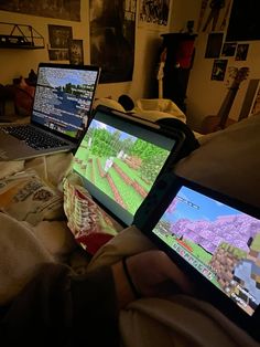 two laptop computers sitting on top of a bed