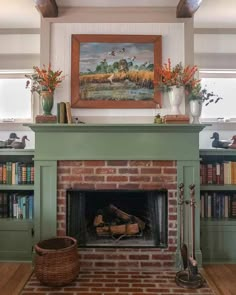 a fireplace in a living room with bookshelves and paintings on the wall above it