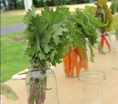 carrots and parsley sit in mason jars on an outdoor table set up for a party