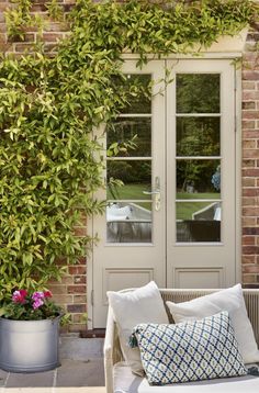 a white couch sitting in front of a door next to a plant filled with flowers